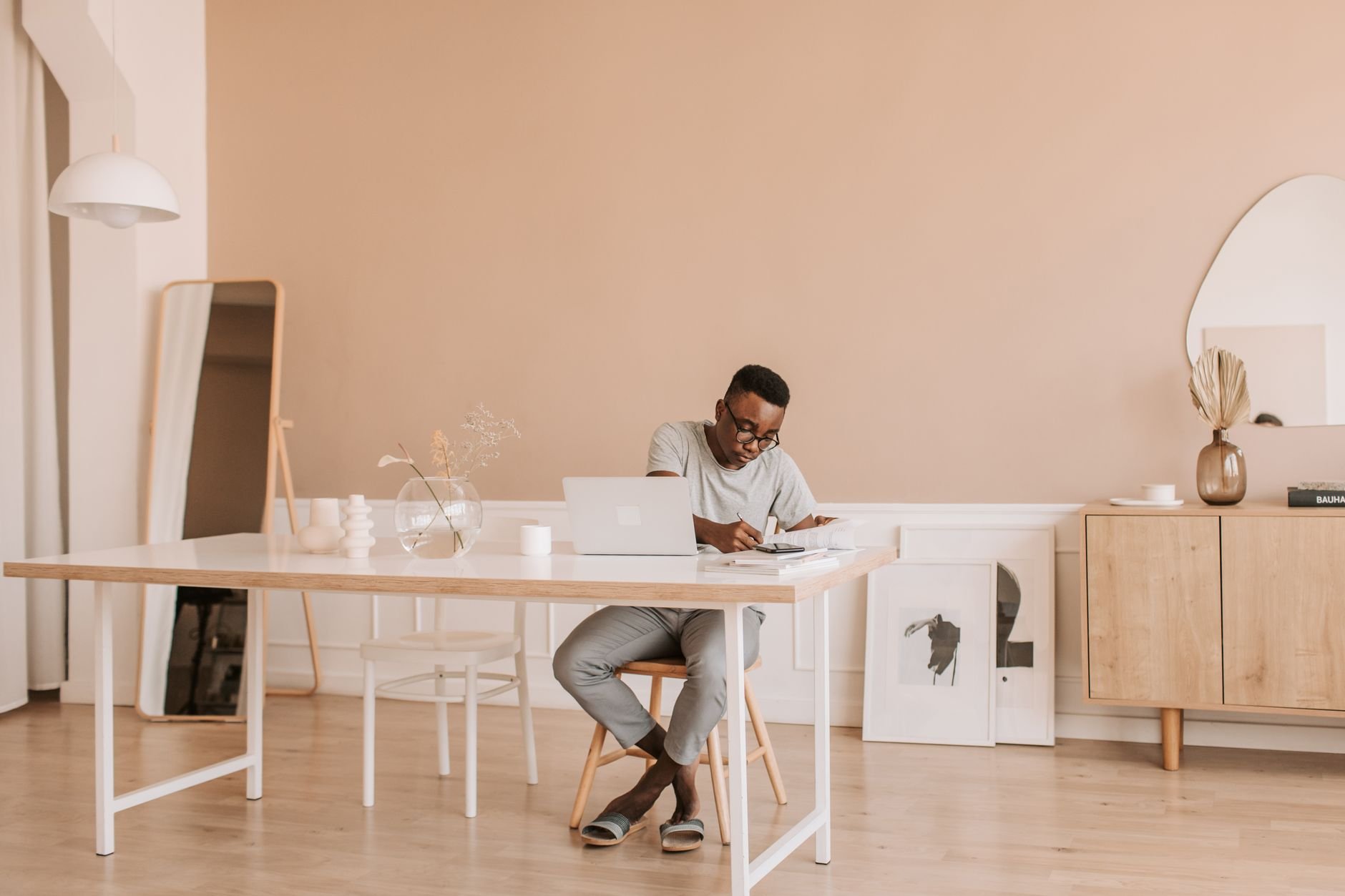Designer working on a laptop at a minimal home office with warm light